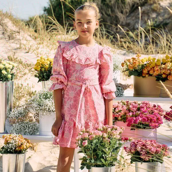 Pale pink cotton dress for girls by classic brand Patachou, patterned with beautiful floral cut work embroidery. It has ruffled trims, puffed sleeves with gently elasticated cuffs and a detachable sash that ties in a bow around the waist.