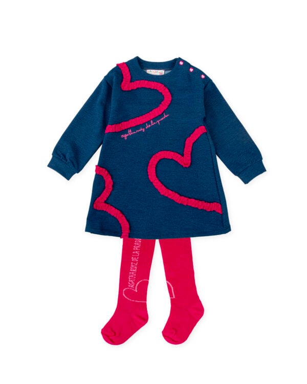 A charming, casual dress set for girls by Agatha Ruiz de la Prada, featuring a plain blue marl dress with vibrant pink ruffle heart detailing. It is made in soft cotton jersey and smaller sizes have poppers on one shoulder for easy dressing. A pair of bright pink tights with a logo and heart motif completes the look.