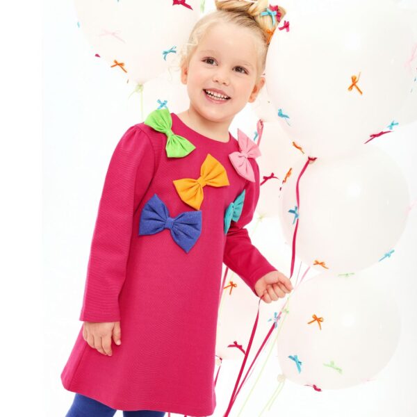 This vibrant fuchsia pink dress set for girls by Agatha Ruiz de la Prada, brings a touch of playful charm to cooler days. Made in soft cotton-blend jersey for comfortable wear, the dress features a delightful array of colourful glittery bows on the front, with popper fastenings on the back. The contrasting bright blue tights have a colourful logo and heart design on the side for a coordinated, cheerful look.