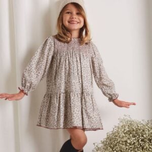 This pretty beige dress for girls by Babidu, has a beautiful leaf print in muted shades of blue and pink. Made in soft cotton twill, it has a sweet ruffled collar and traditional smocking across the bodice. Fully lined in voile for comfort, the long, puffed sleeves have gently elasticated, frilled cuffs.