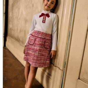 This stylish dress for girls by Patachou, features a chic combination of textures in ivory and red. The ribbed jersey bodice has a delicate silver shimmer and a high neckline, while the tweed skirt adds a touch of classic charm. Velvet-trimmed pockets and a lovely red velvet bow, embellished with sparkling crystal buttons, complete the look. Fully lined for comfort, the dress fastens neatly on the back with a concealed zip.