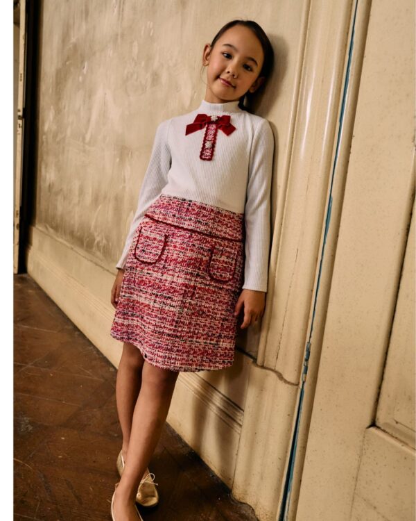 This stylish dress for girls by Patachou, features a chic combination of textures in ivory and red. The ribbed jersey bodice has a delicate silver shimmer and a high neckline, while the tweed skirt adds a touch of classic charm. Velvet-trimmed pockets and a lovely red velvet bow, embellished with sparkling crystal buttons, complete the look. Fully lined for comfort, the dress fastens neatly on the back with a concealed zip.