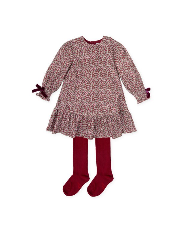 Girls red needlecord dress by Tutto Piccolo, with a pretty white and green floral pattern. The puffed sleeves have sweet shirred cuffs and burgundy red velvet trims. With a cute, ruffled hemline, the dress is fully lined for comfort and comes with a pair of soft cotton-blend, burgundy red tights to complete the look.